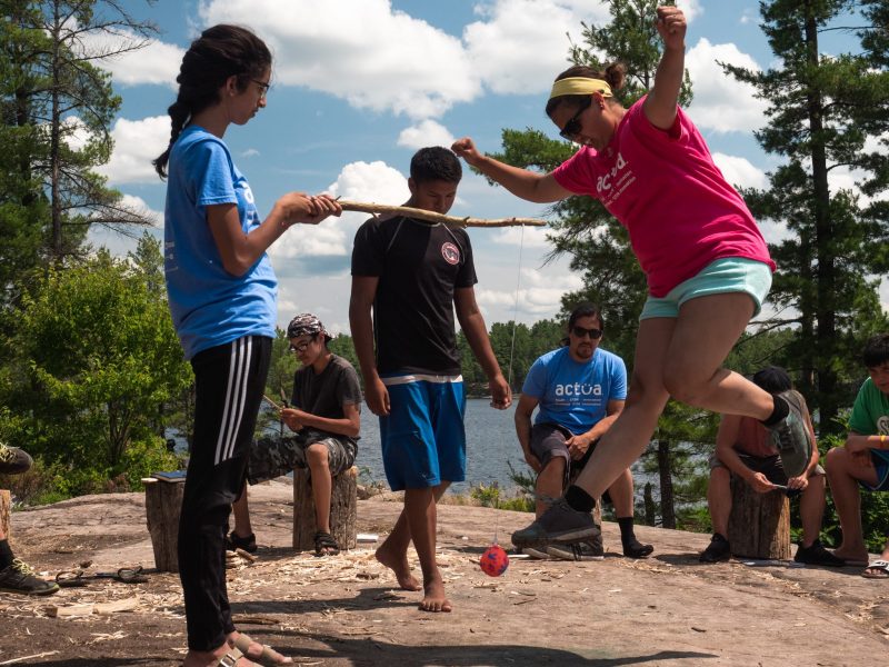 Youth playing outdoors with a stick and ball.