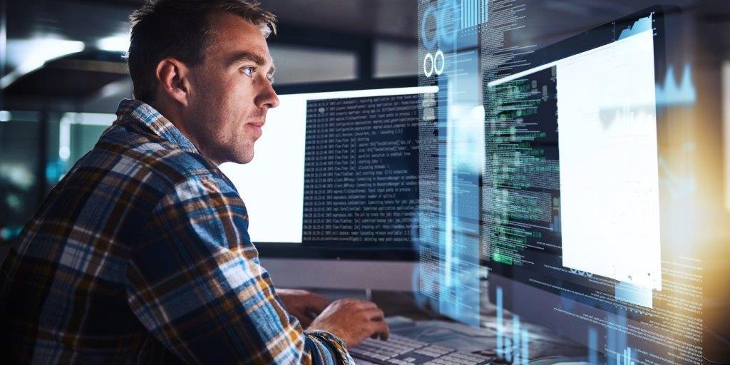 A man coding on two screens.