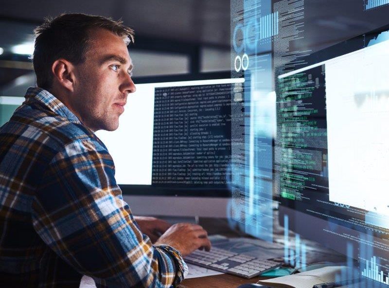 A man coding on two screens.