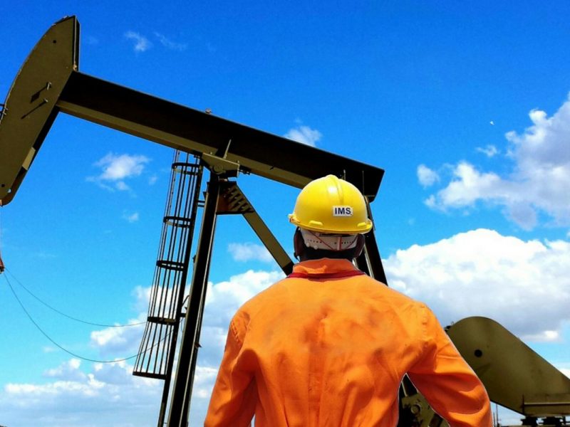 A worker looking up at an oil rig.