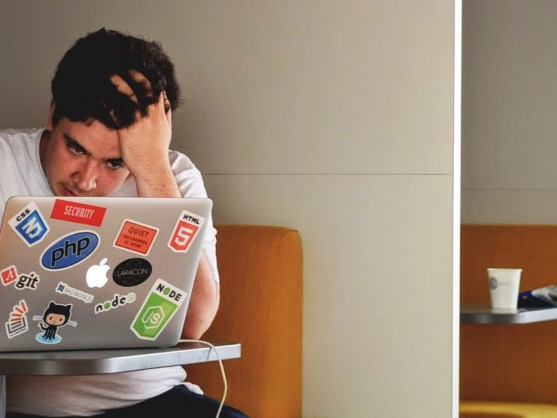 An individual stressfully holding their head up as they look at their laptop.