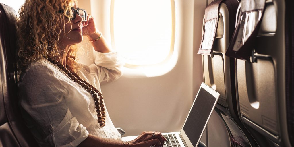 An Individual using a laptop on an airplane