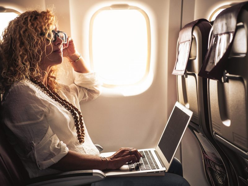 Photo of an Individual using a laptop on an airplane