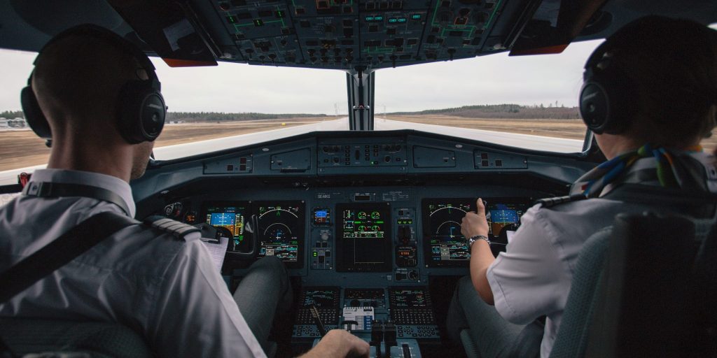 Two pilots sit in a cockpit on the runway preparing for flight.