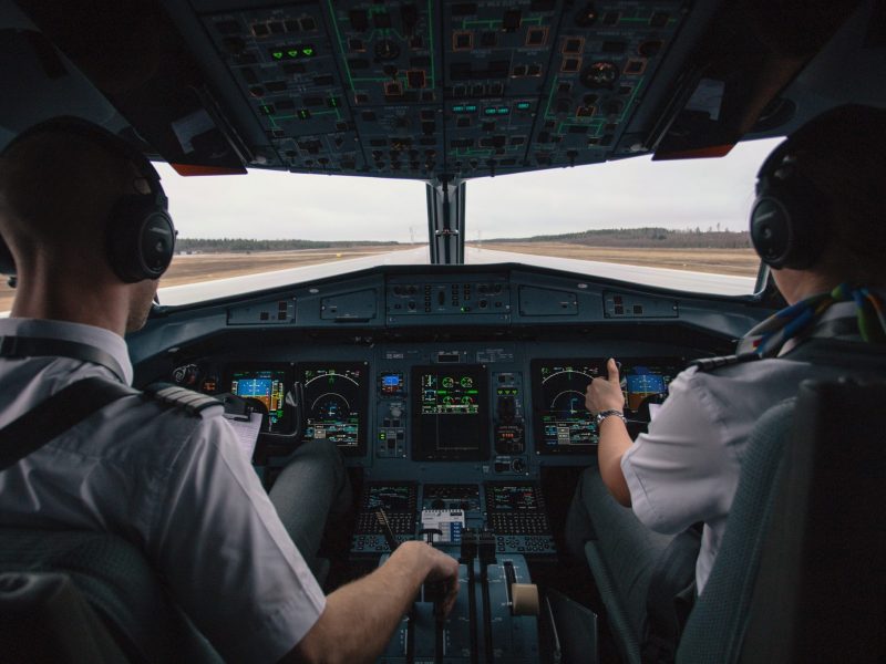 Two pilots sit in a cockpit on the runway preparing for flight.