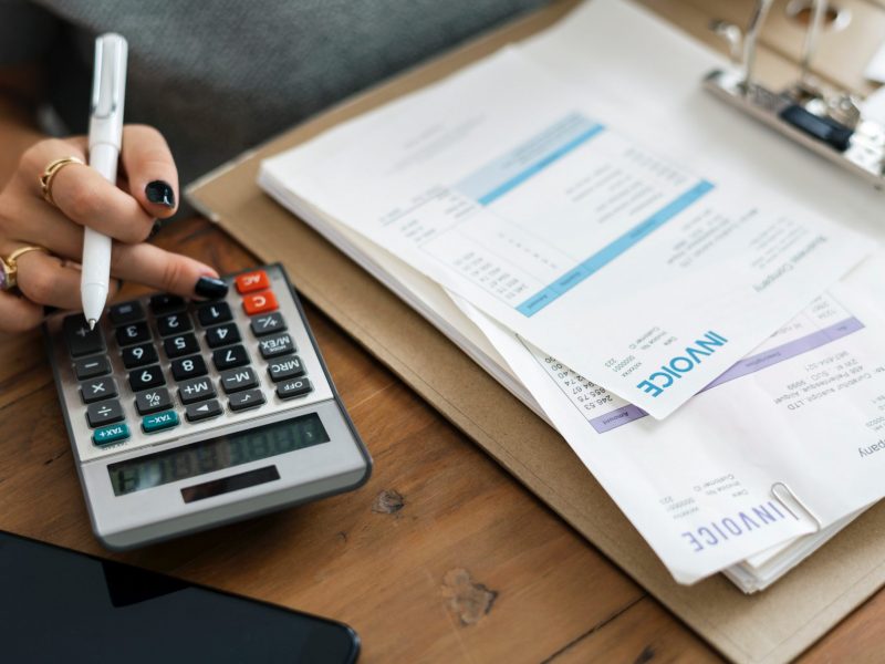 professional individual working with a calculator and invoice papers.