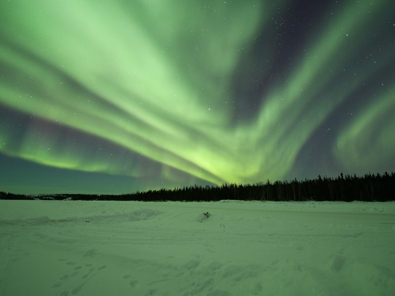 a snowy field with northern lights.