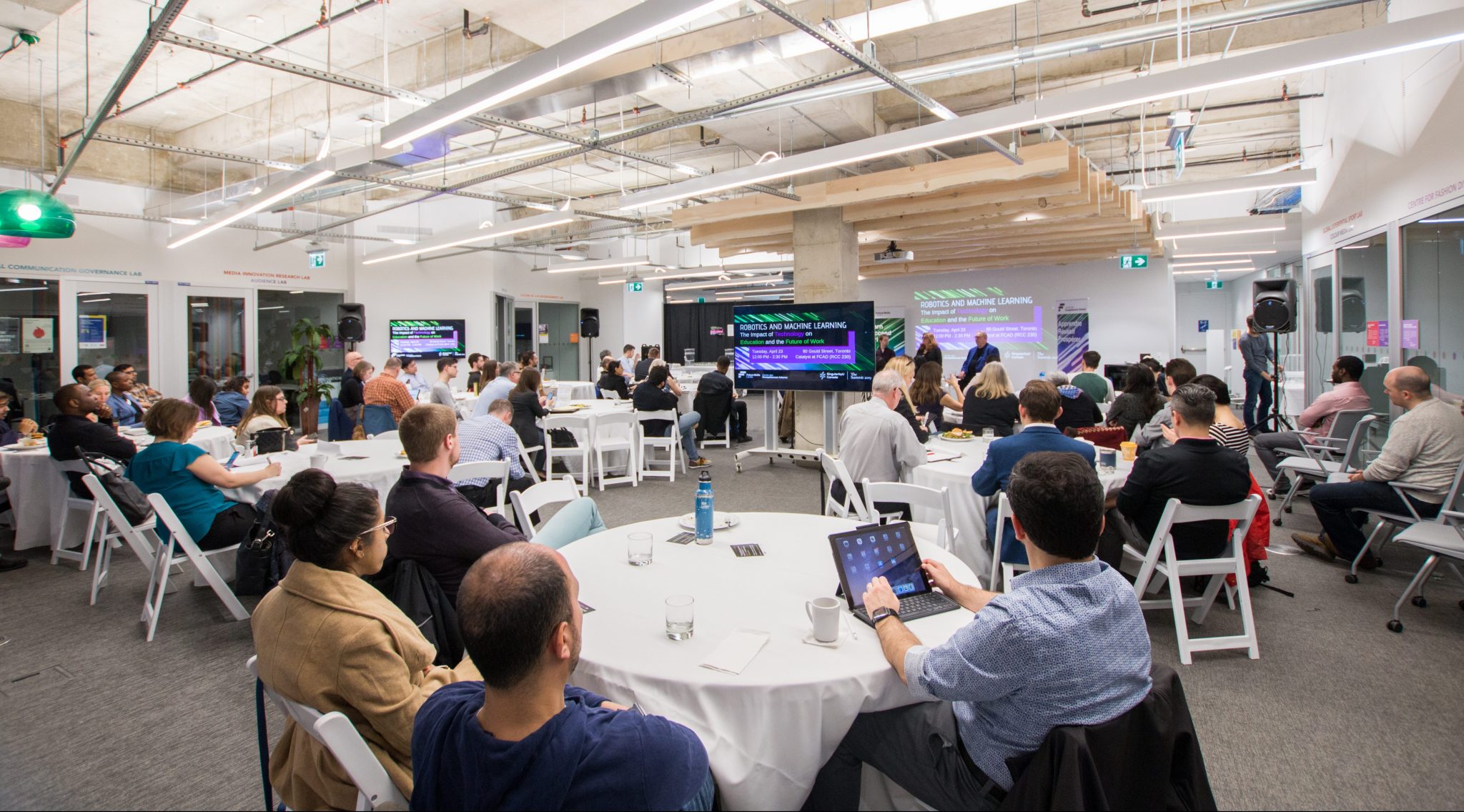 A large group of individuals listening to a panel.