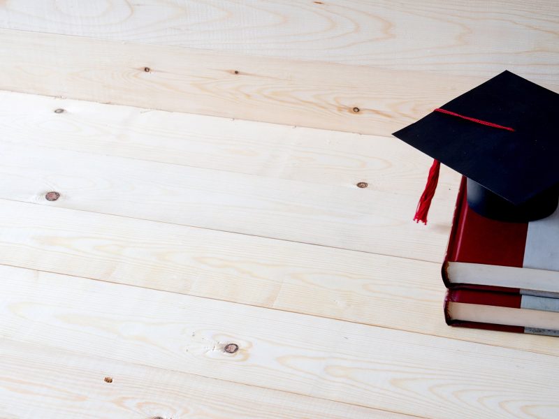 Graduation cap with graduation paper on a stack of book