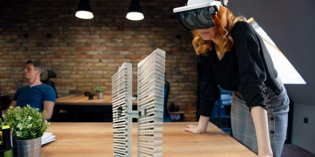 An individual wearing an augmented reality headset to visualize two office towers