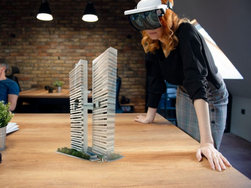 An individual wearing an augmented reality headset to visualize two office towers