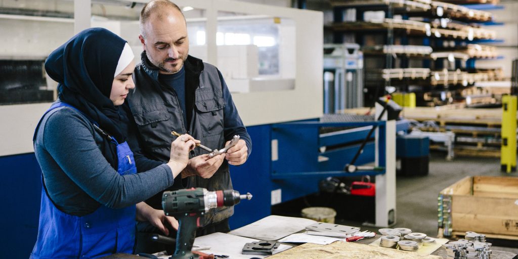 teamwork: technician explains a work tool to a young woman in a workshop