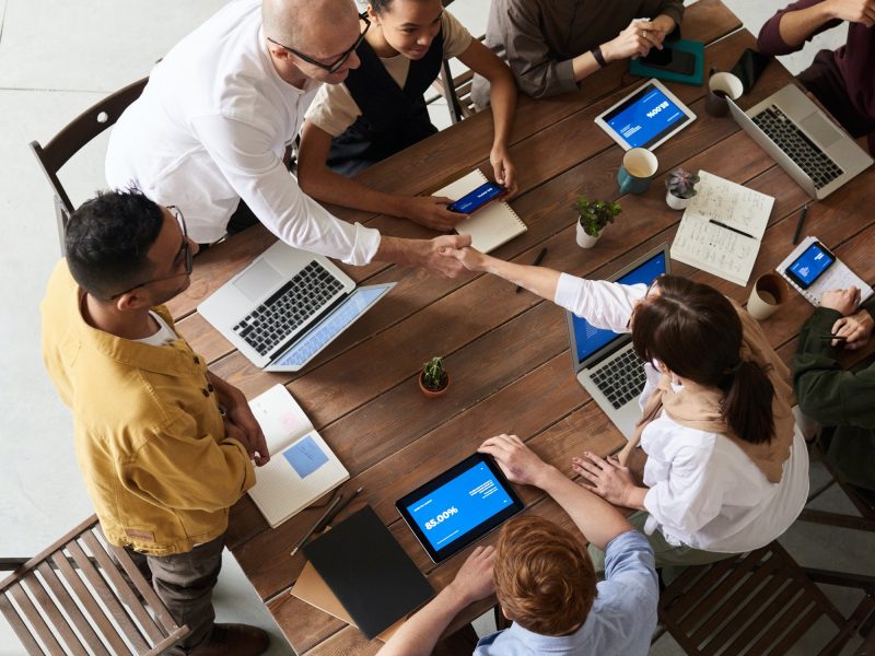 Birds-eye view of a meeting with a group of professionals. Two of them shaking hands.