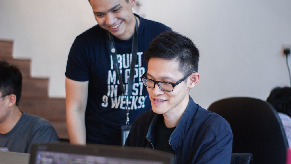 Person at computer with someone standing behind them looking at the screen