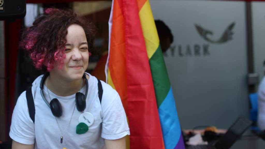 Young person in front of Pride flag