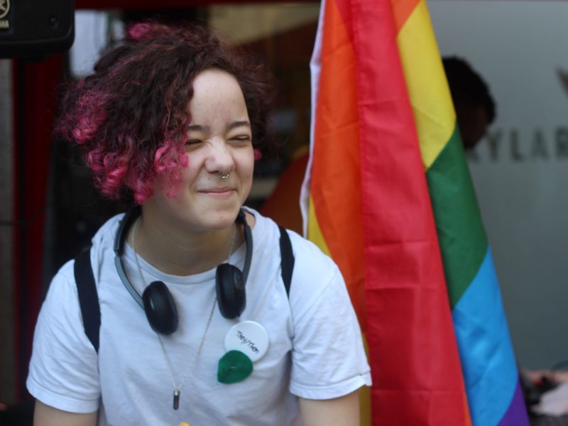 Young person in front of Pride flag