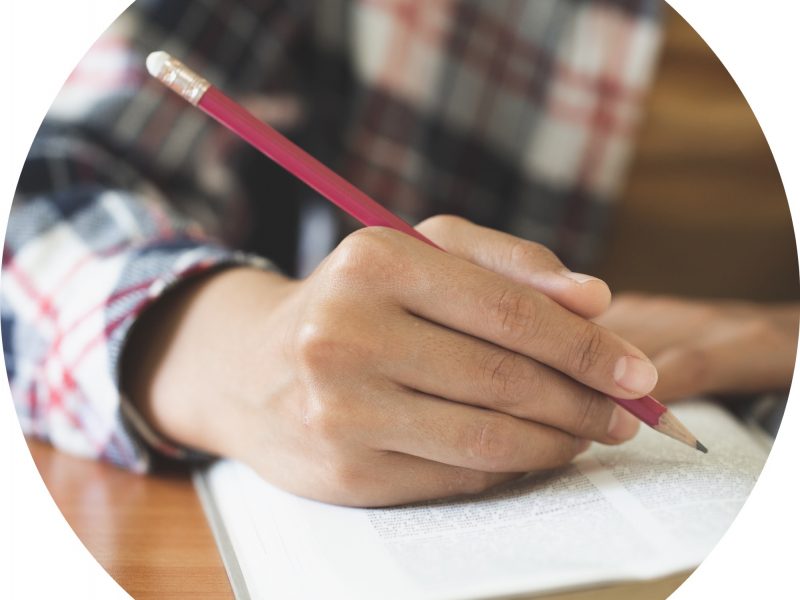 detailed image of a man's hand writing in a book.