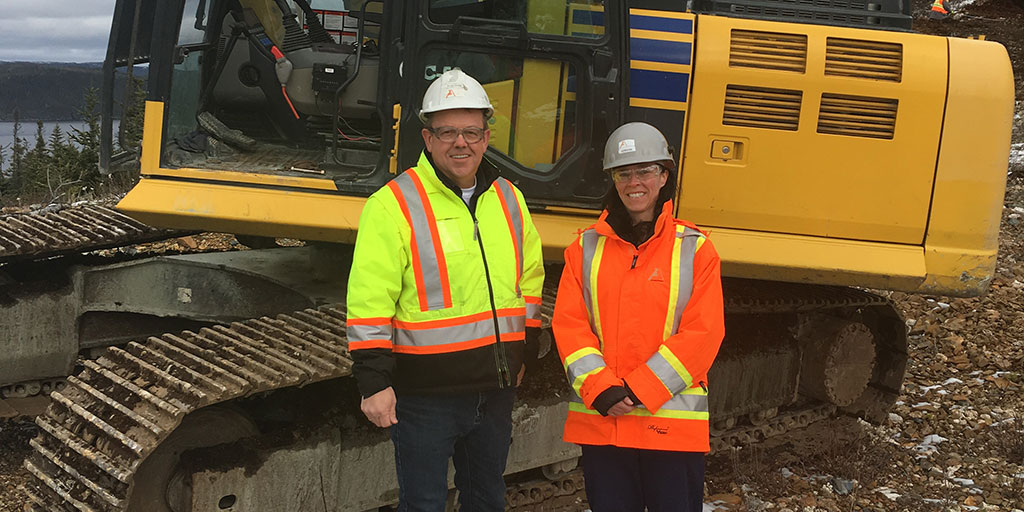 Two miners infront of heavy equipment