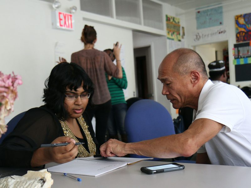 Mentor providing learning support to mentee in a classroom.