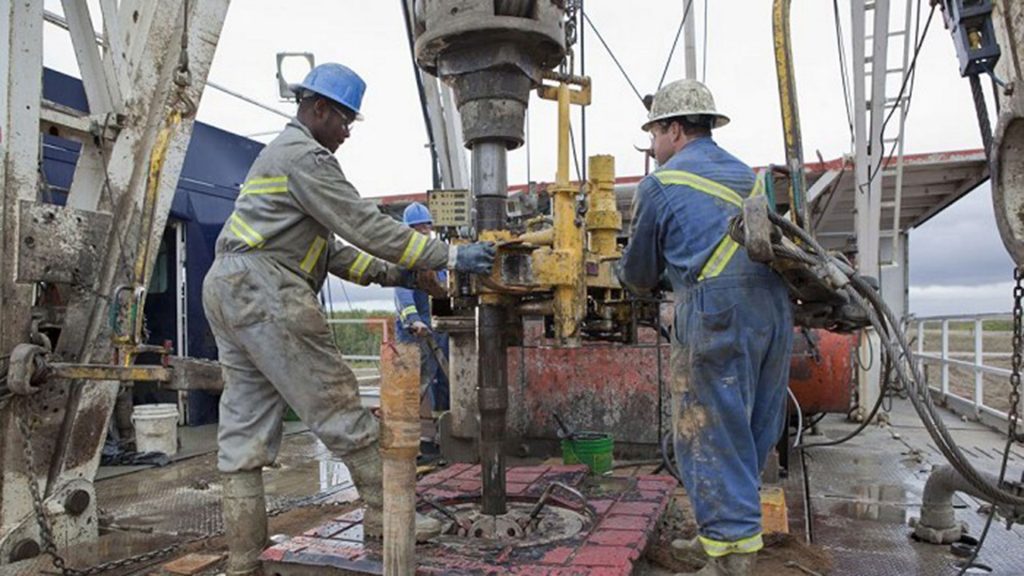 Two energy workers handling large machinery