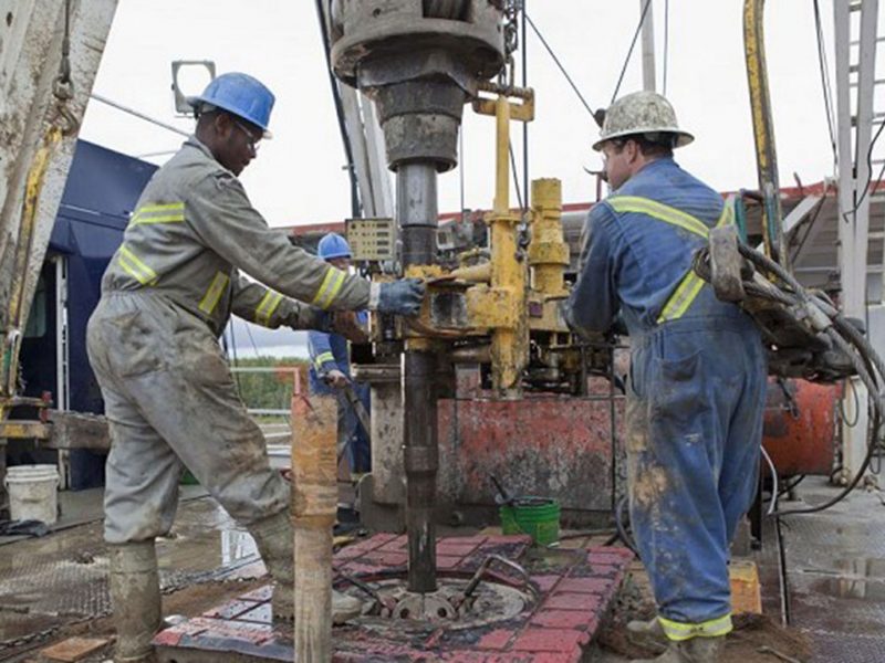 Two energy workers handling large machinery