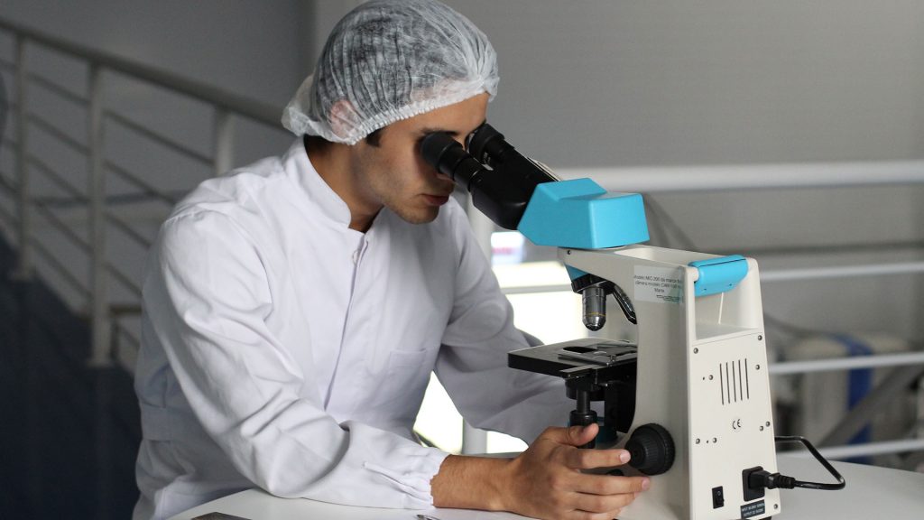 Scientist looking at specimen through a compound microscope