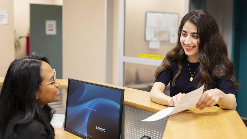 Women coworkers discussing a document at a reception desk