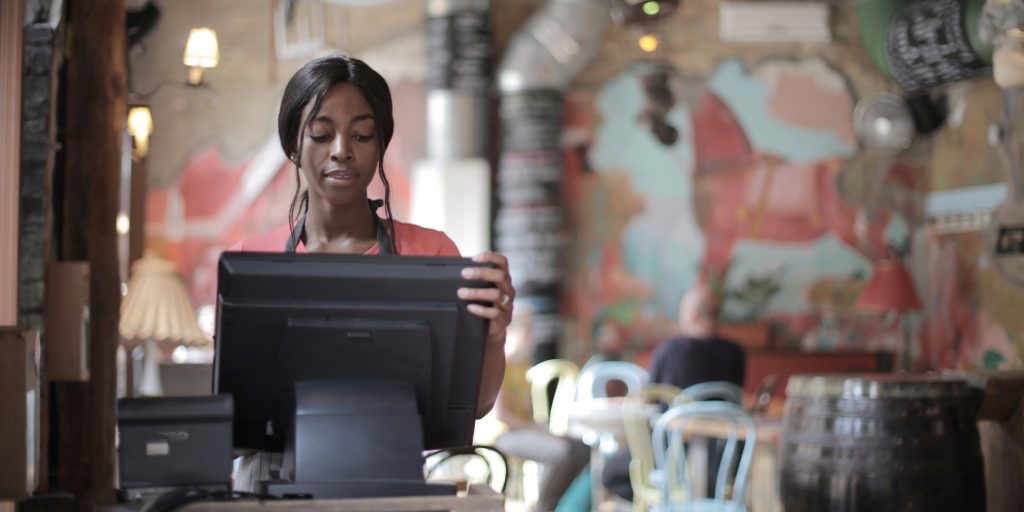 Cashier at restaurant working on a computer.