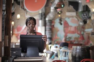 Cashier at restaurant working on a computer.