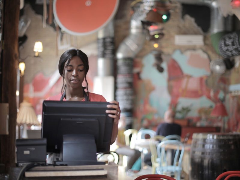 Cashier at restaurant working on a computer.