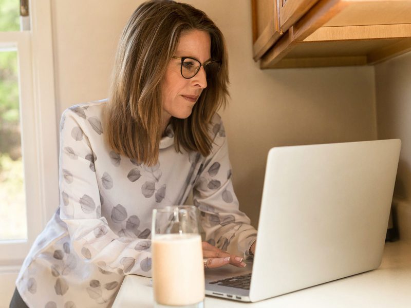 Person standing at a counter and working on their laptop