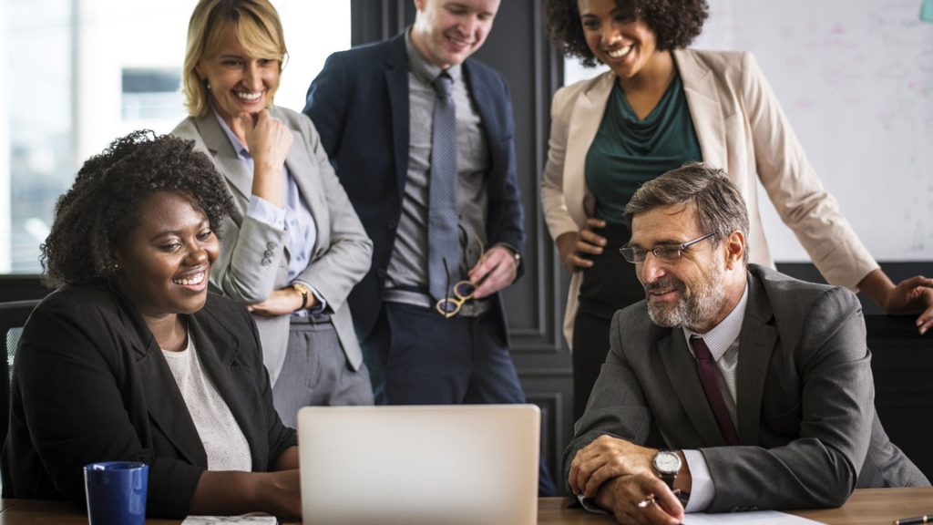 Colleagues smiling while looking at a laptop