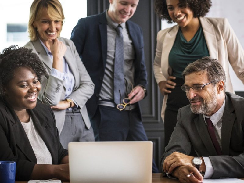 Colleagues smiling while looking at a laptop