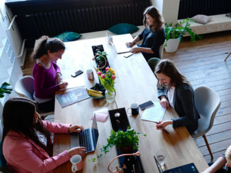 Group of women sitting at a table on their laptops