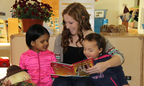 Women holding toddler in lap reading a book.