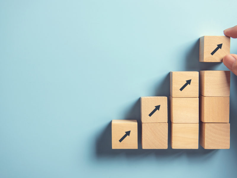 Hand arranging wood block stacking as step stair on paper pink background. Business concept growth success process, copy space.