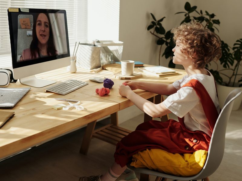 Young student video conferencing his teacher through a computer