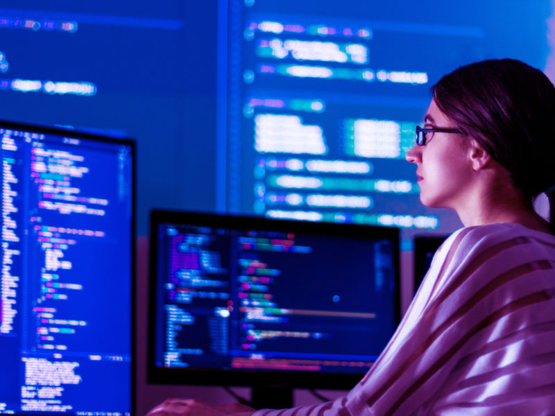 Woman looking at computer and coding.