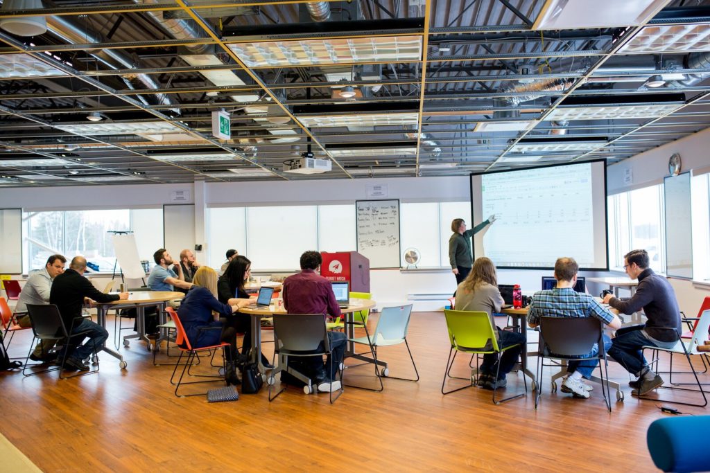 Classroom filled with students and instructor pointing to board.