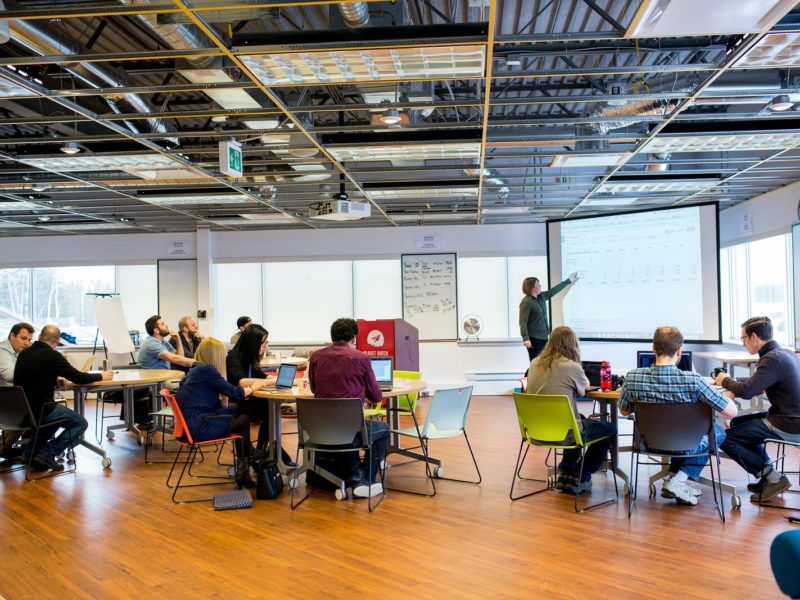 Classroom filled with students and instructor pointing to board.