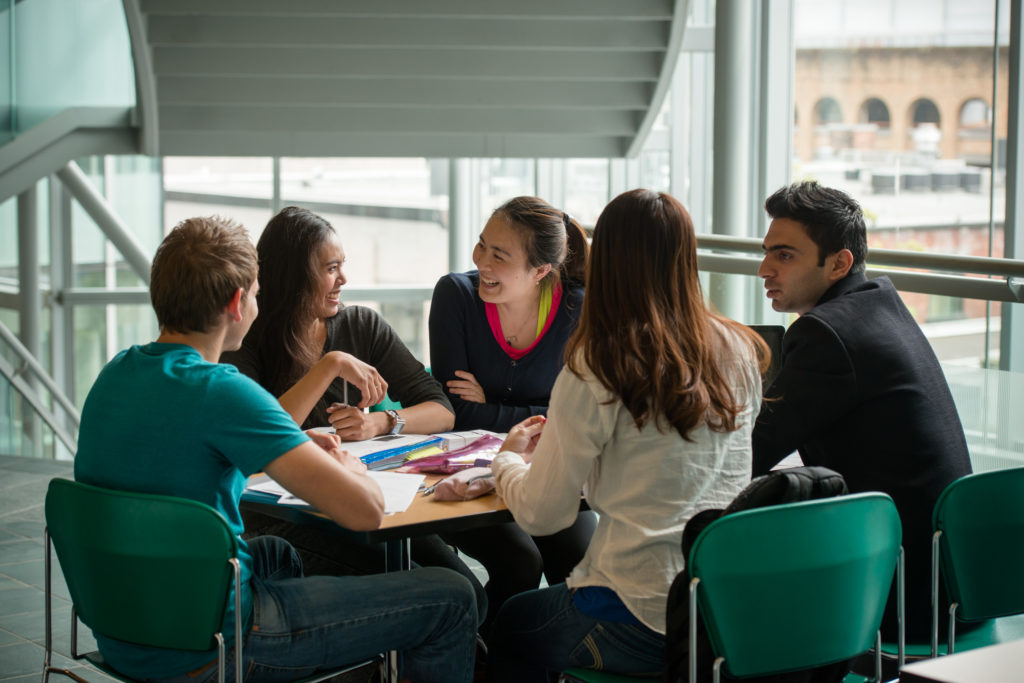 Group of students around a table smiling.