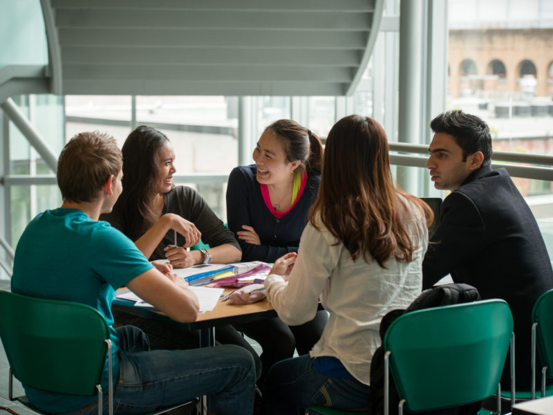 Group of students around a table smiling.