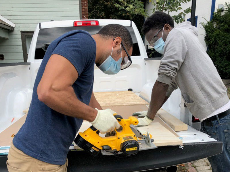 Two gentlemen sawing a piece of wood together. 