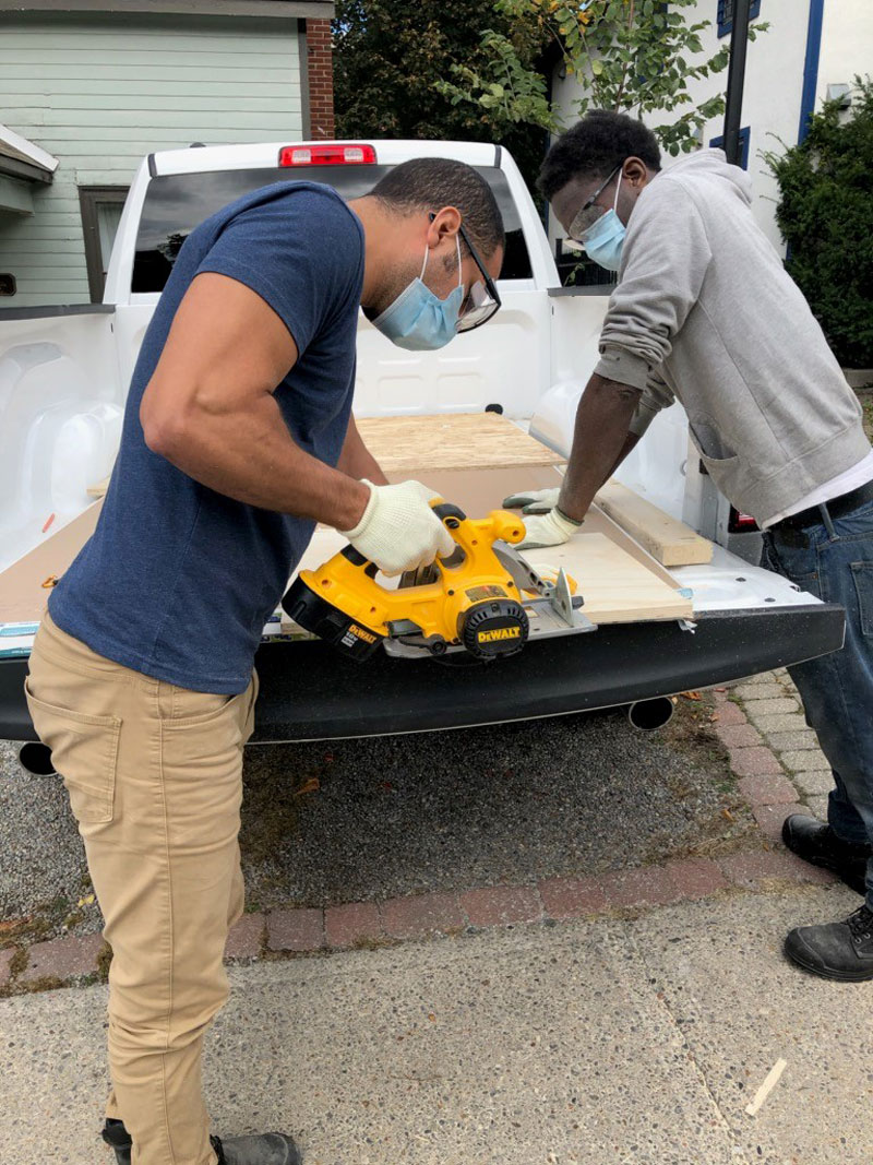 Two gentlemen sawing a piece of wood together.