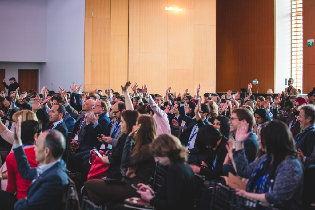 Large group of individuals raising their hands in participation. 