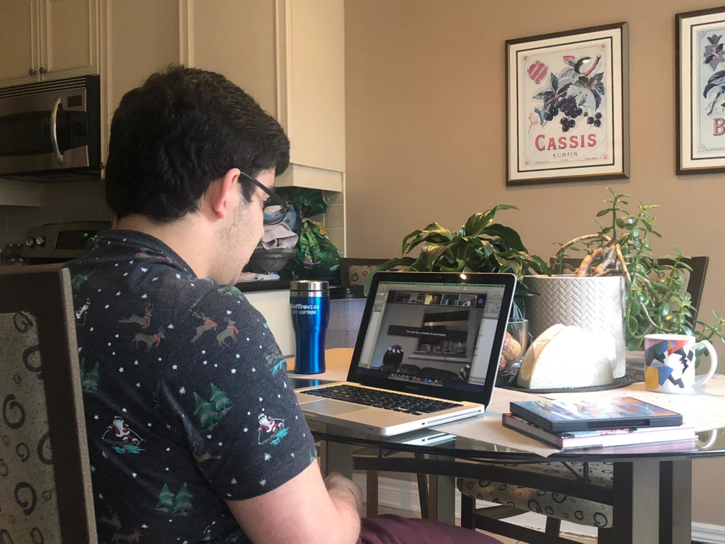 Student participating in online course at home with laptop on dining table.