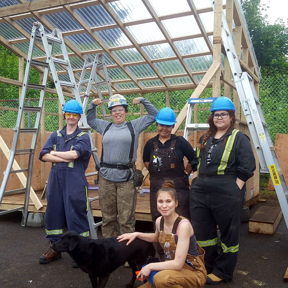 Women in construction gear standing infront of a building frame.