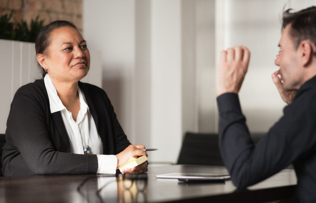 Two individuals in a meeting room having a discussion.