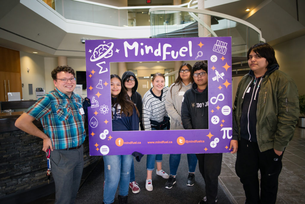 Highschool students holding up sign with science symbols.