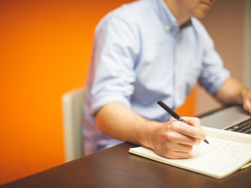 Photograph of Person writing on desk